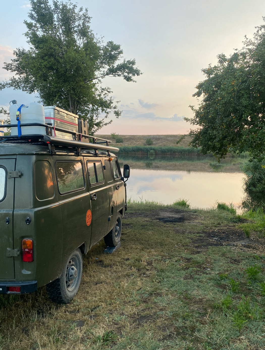 UAZ Buchanka an einem ruhigen See bei Sonnenuntergang